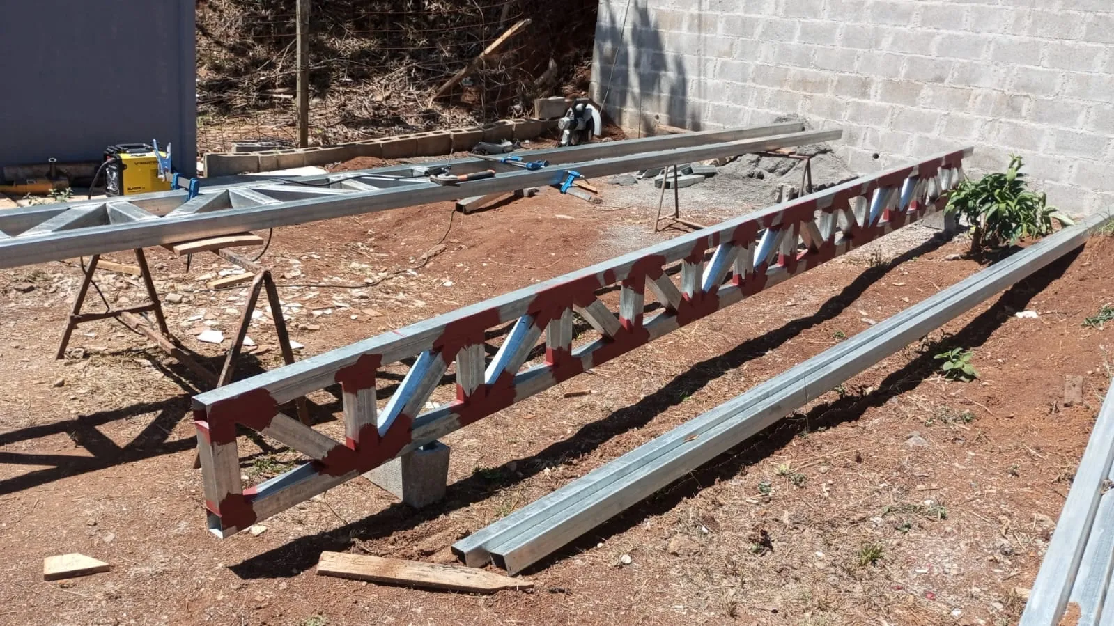 Cerchas metálicas Pratt sobre caballetes en sitio de obra industrial.