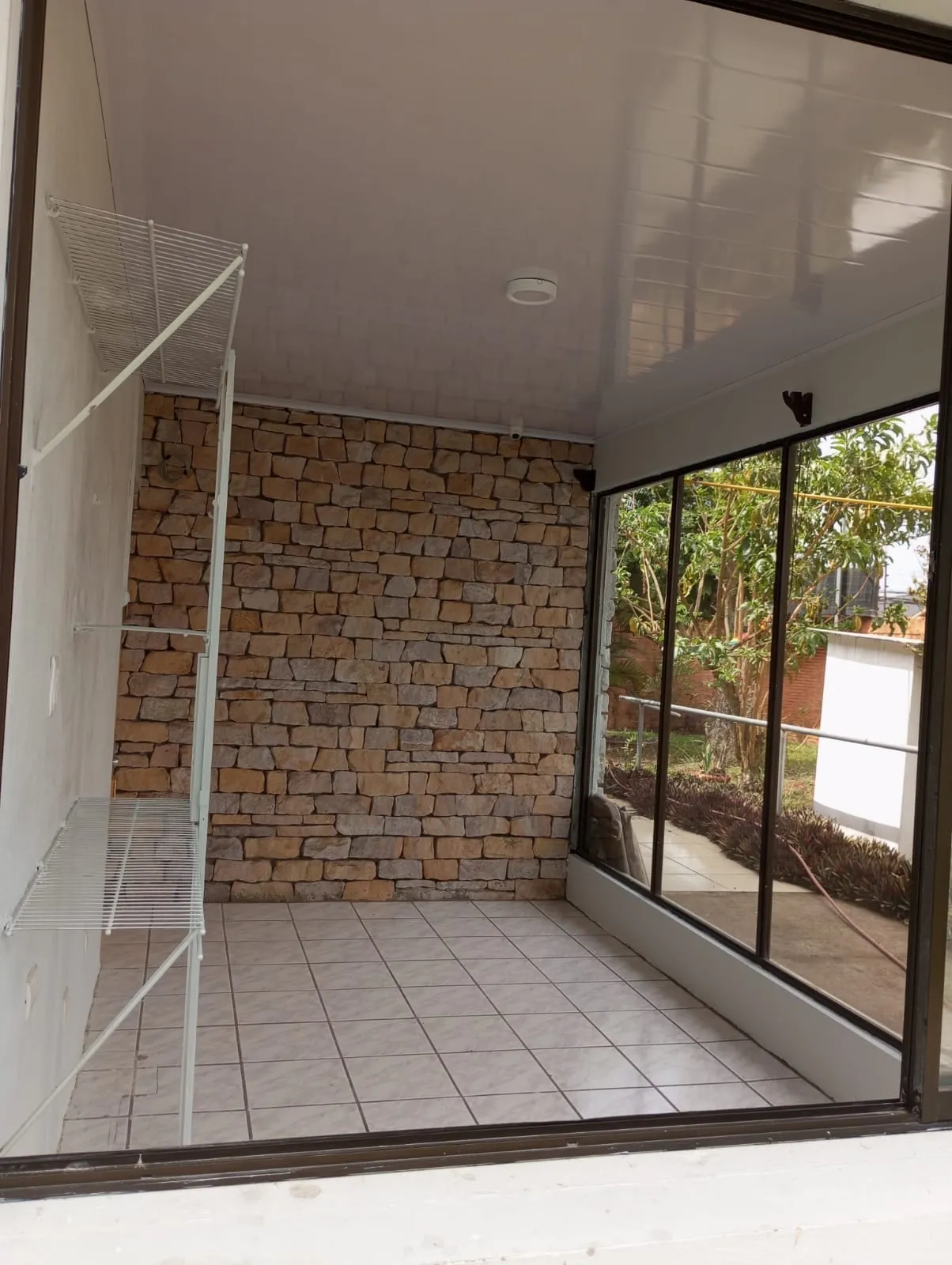 Sala remodelada con muro de piedra natural y ventanal corredizo de aluminio.
