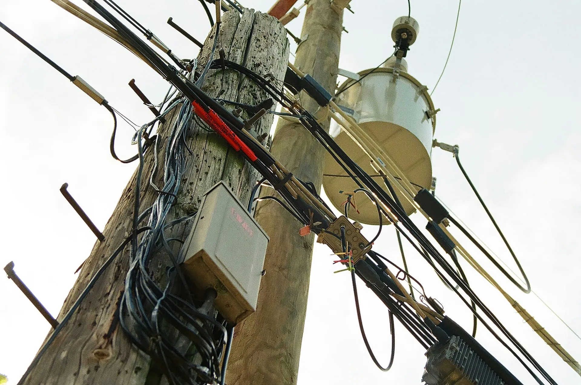 Poste con cableado de telecomunicaciones, transformador y enlaces externos.